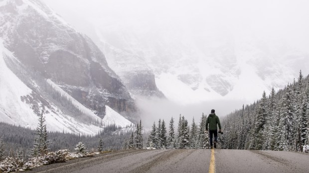WEB—Photographer-walks-down-a-road-in-the-winter-with-his-camera—shutterstock_499404463