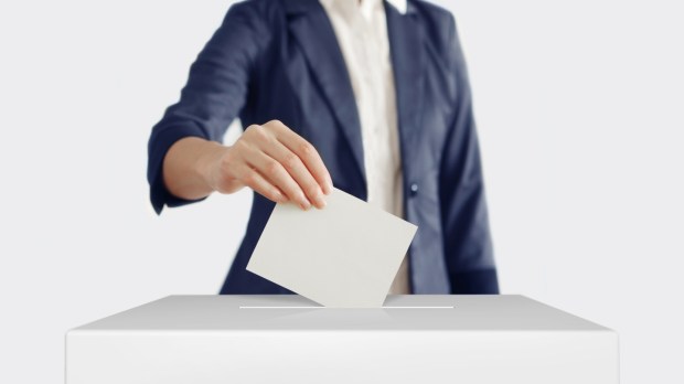 Femme glissant son bulletin de vote dans l'urne