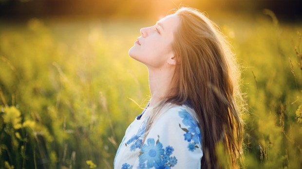 WEB3-WOMAN-FIELD-GREEN-SUNSET-LOOKING-UP-RELAX-HOPE-Shutterstock