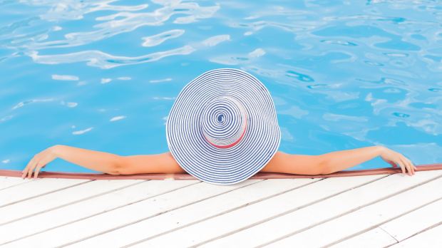 FEMME A CHAPEAU DE DOS DANS UNE PISCINE