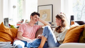 Uśmiechnięta para rozmawia ze sobą w domu na kanapie