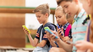 web3-primary-education-friendship-childhood-technology-and-people-concept-group-of-happy-elementary-school-students-with-smartphones-and-backpacks-sitting-on-bench-outdoors-shut