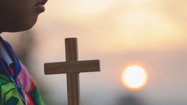 WEB3-Boy-hands-holding-holy-cross-praying-God