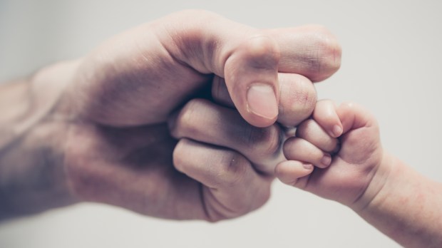 Fist of Dad and Newborn Baby