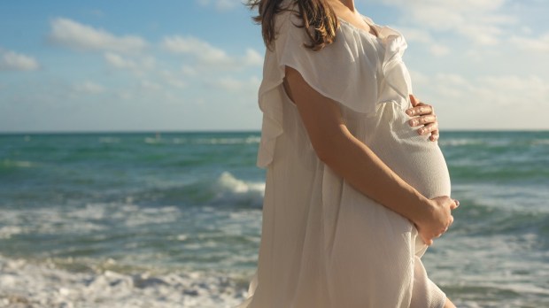 Happy Young Pregnant Woman on the Beach at the Atlantic Ocean
