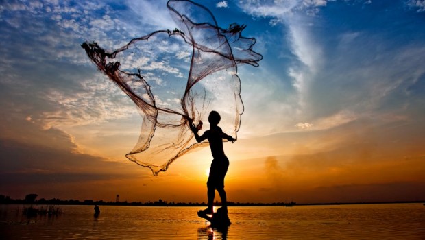 throwing fishing net during sunset , thai